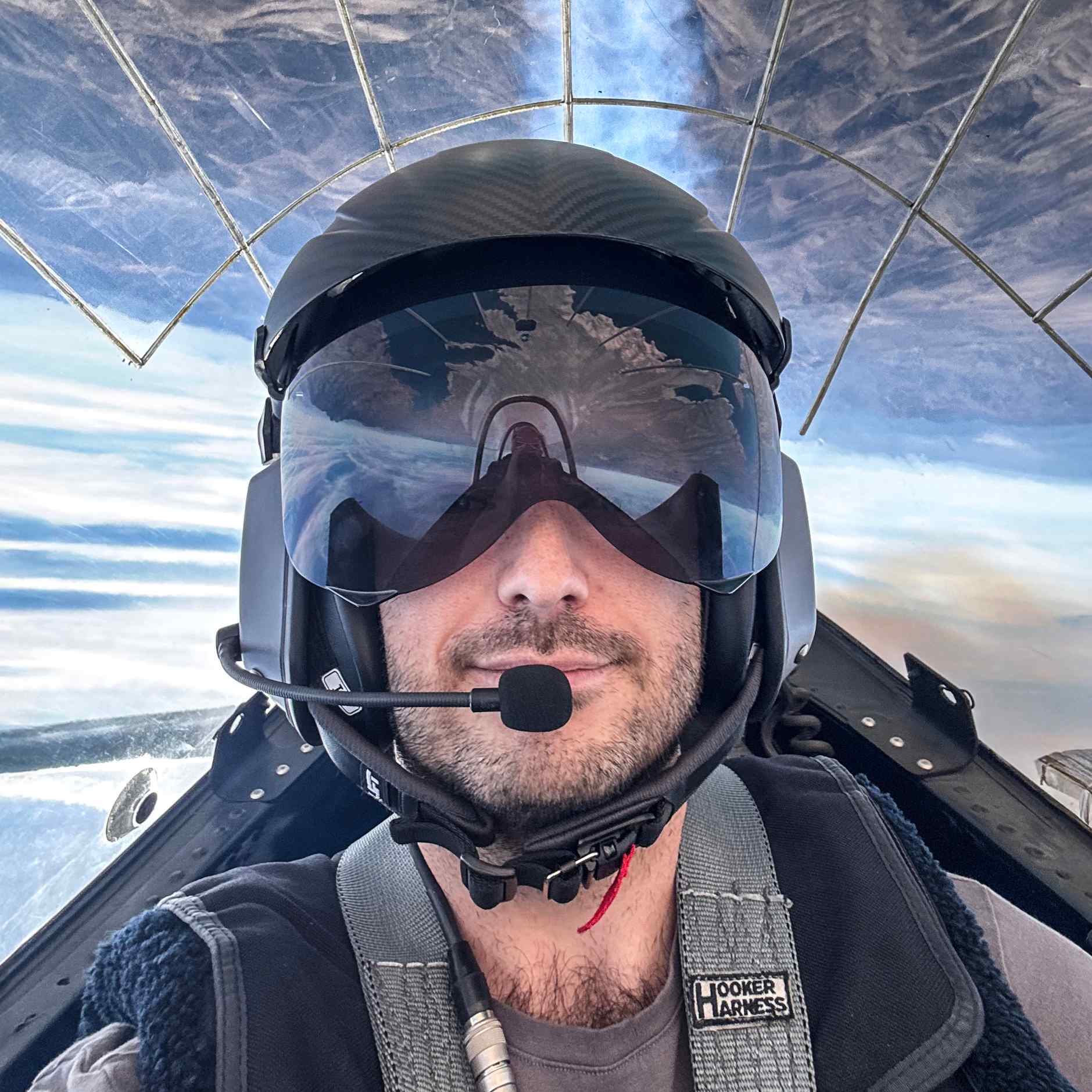 Aviation photographer Billy Hardiman inside an aerobatic airplane cockpit, flying inverted with a reflective visor and flight helmet.