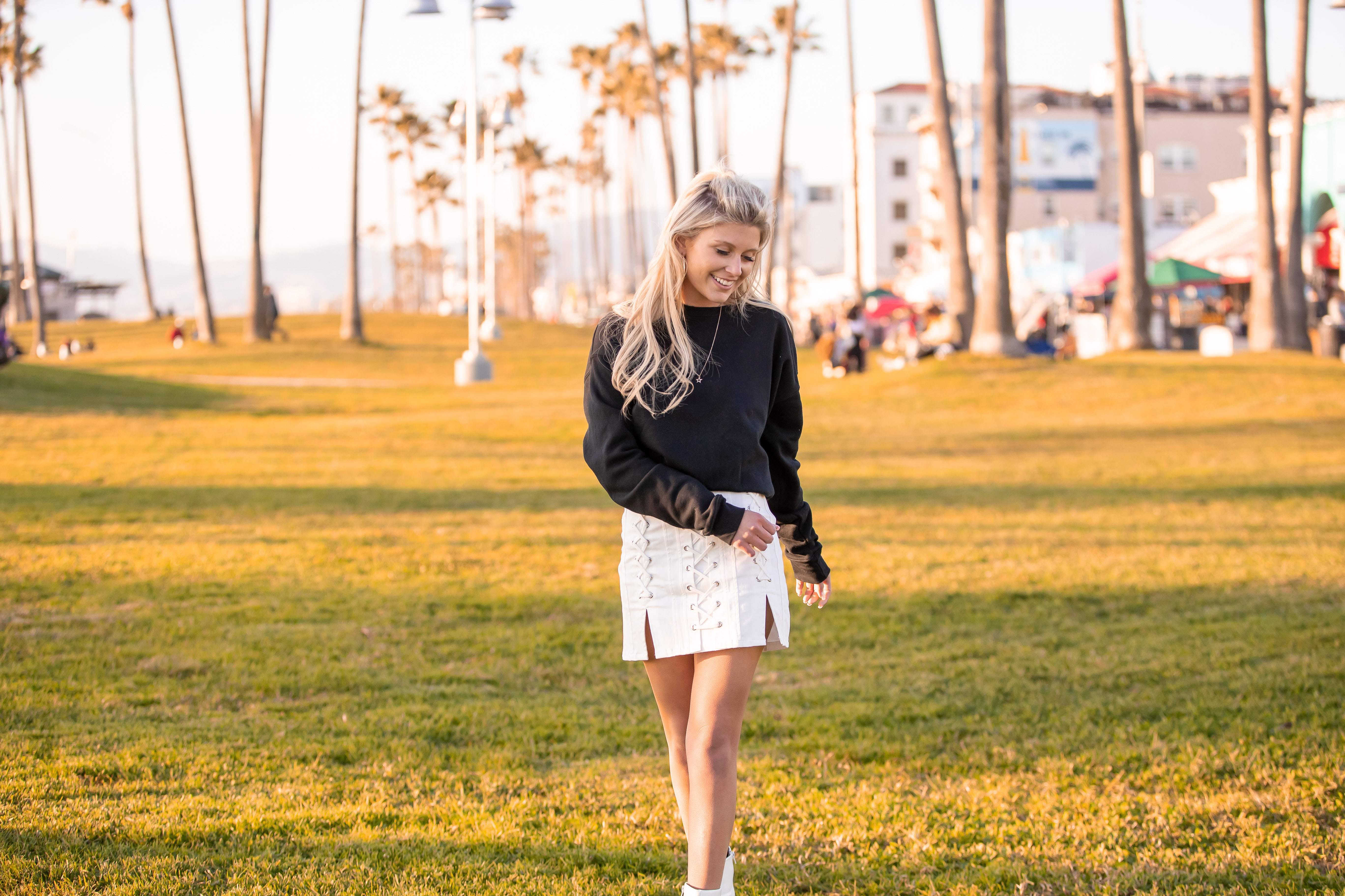 Young woman strolling through the grass near Venice Beach Boardwalk at sunset in Los Angeles, California