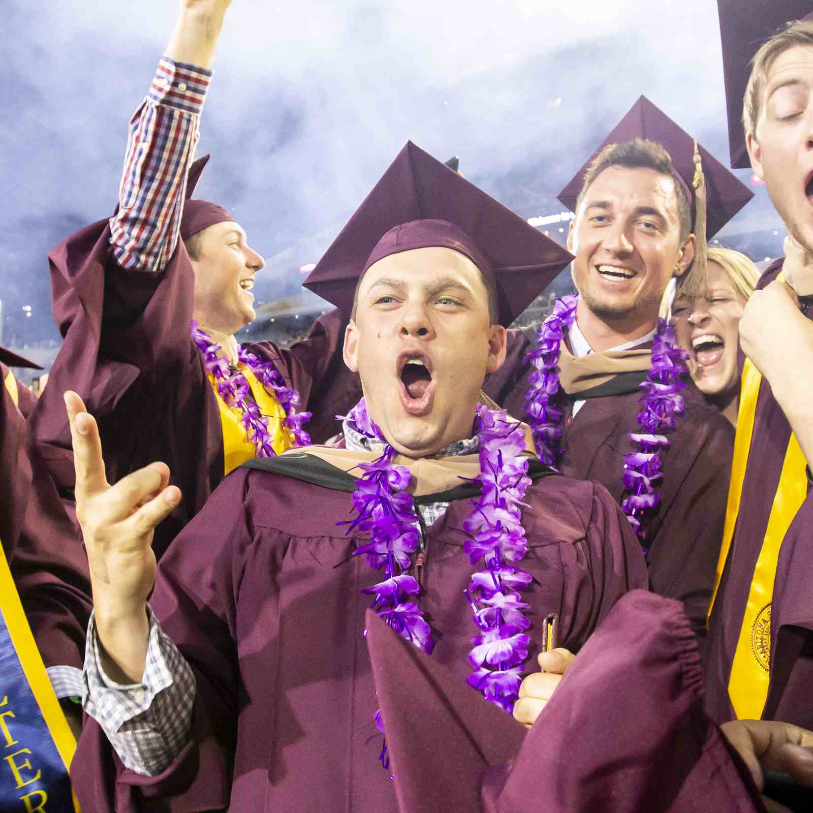 Group of graduates celebrating with diplomas during Arizona State University commencement in Tempe, Arizona