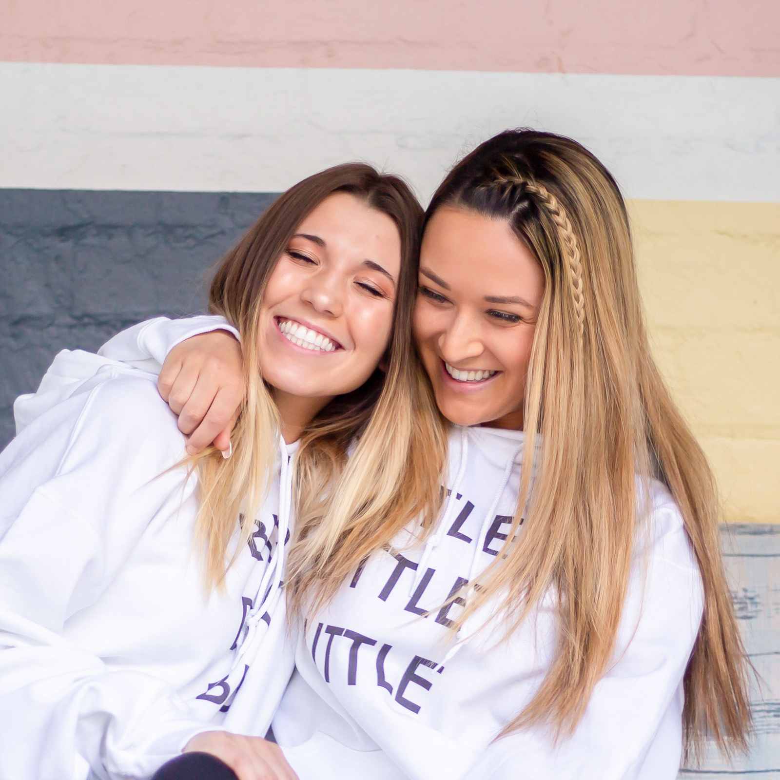 Two college sorority friends hugging on a couch in a lounge in Beverly Hills, California