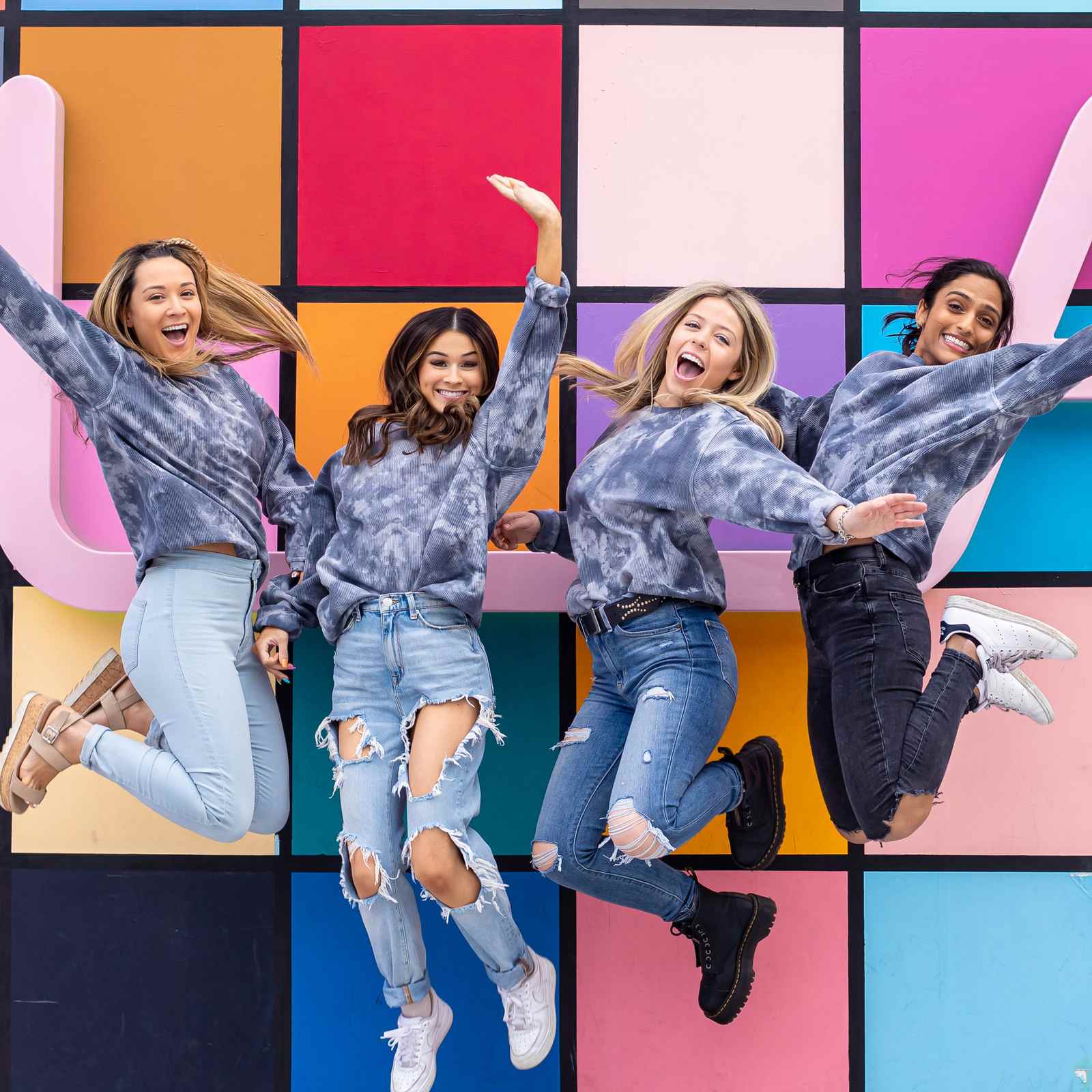 College sorority friends jumping in front of a colorful mural at Westfield Century City in Los Angeles, California