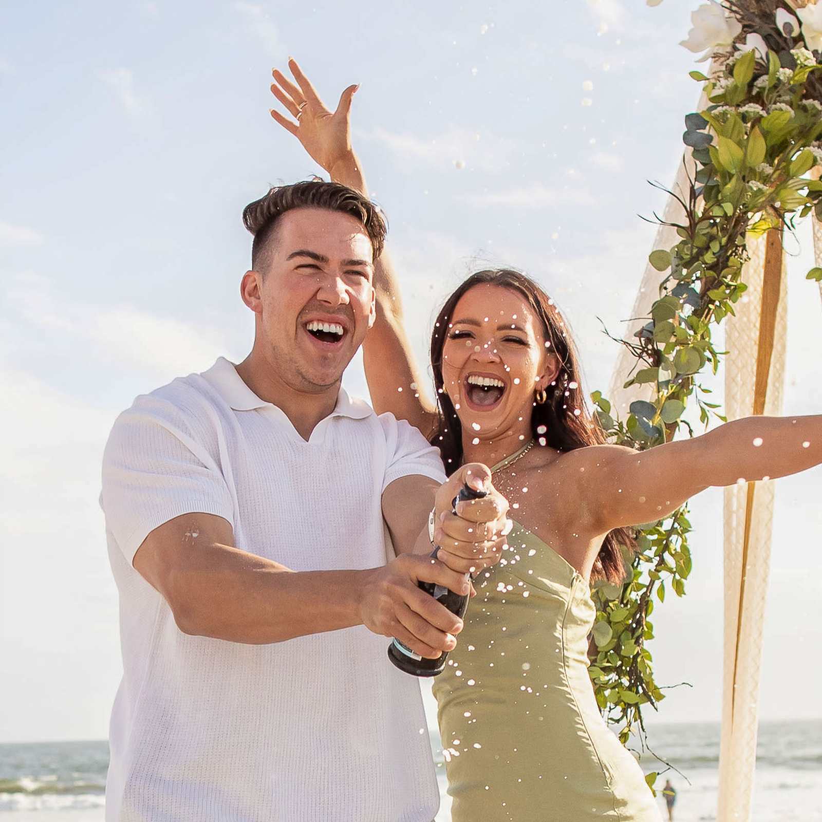 Young couple popping champagne in celebration on Coronado Beach