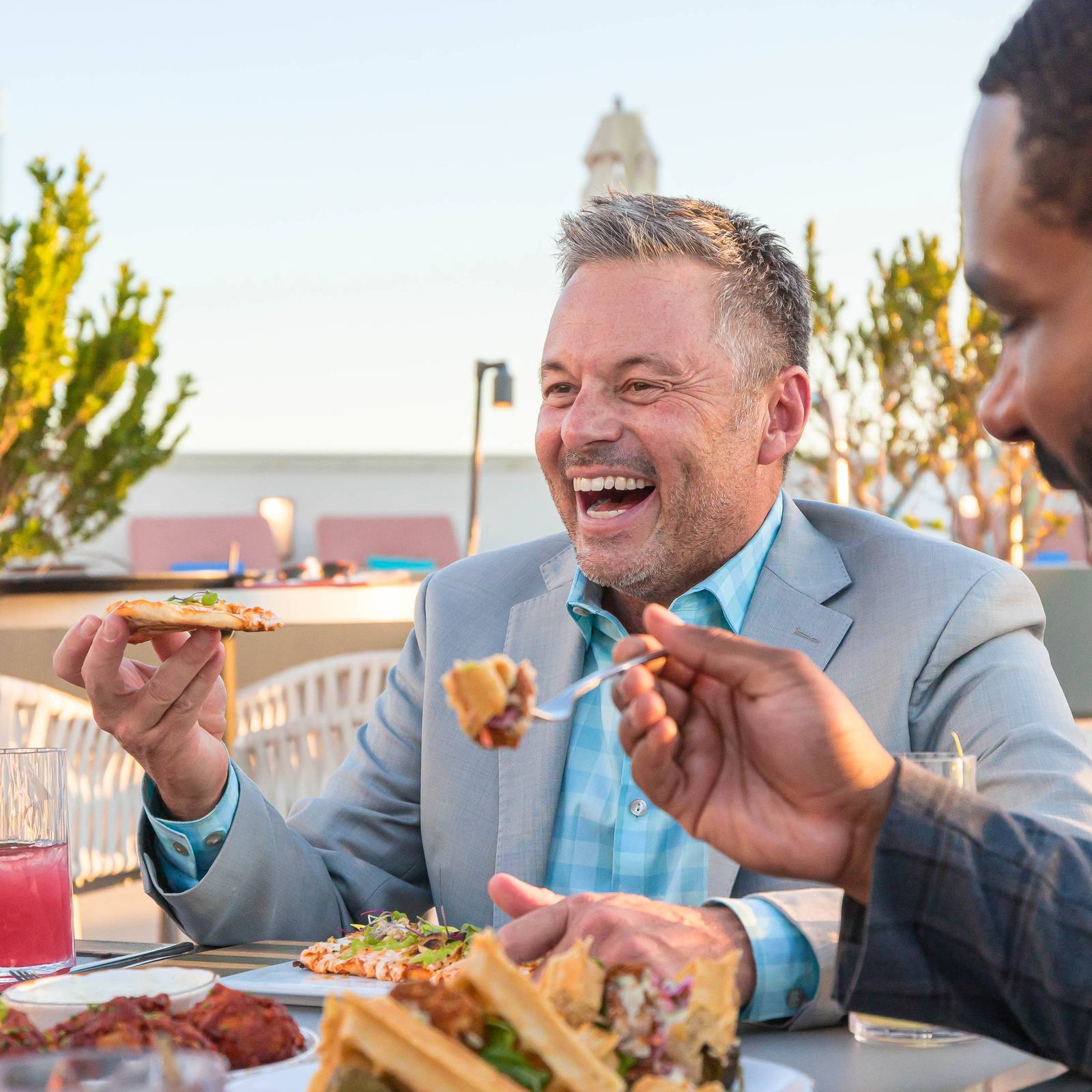 Group of friends laughing over lunch at Skysill Rooftop Lounge in Tempe, Arizona