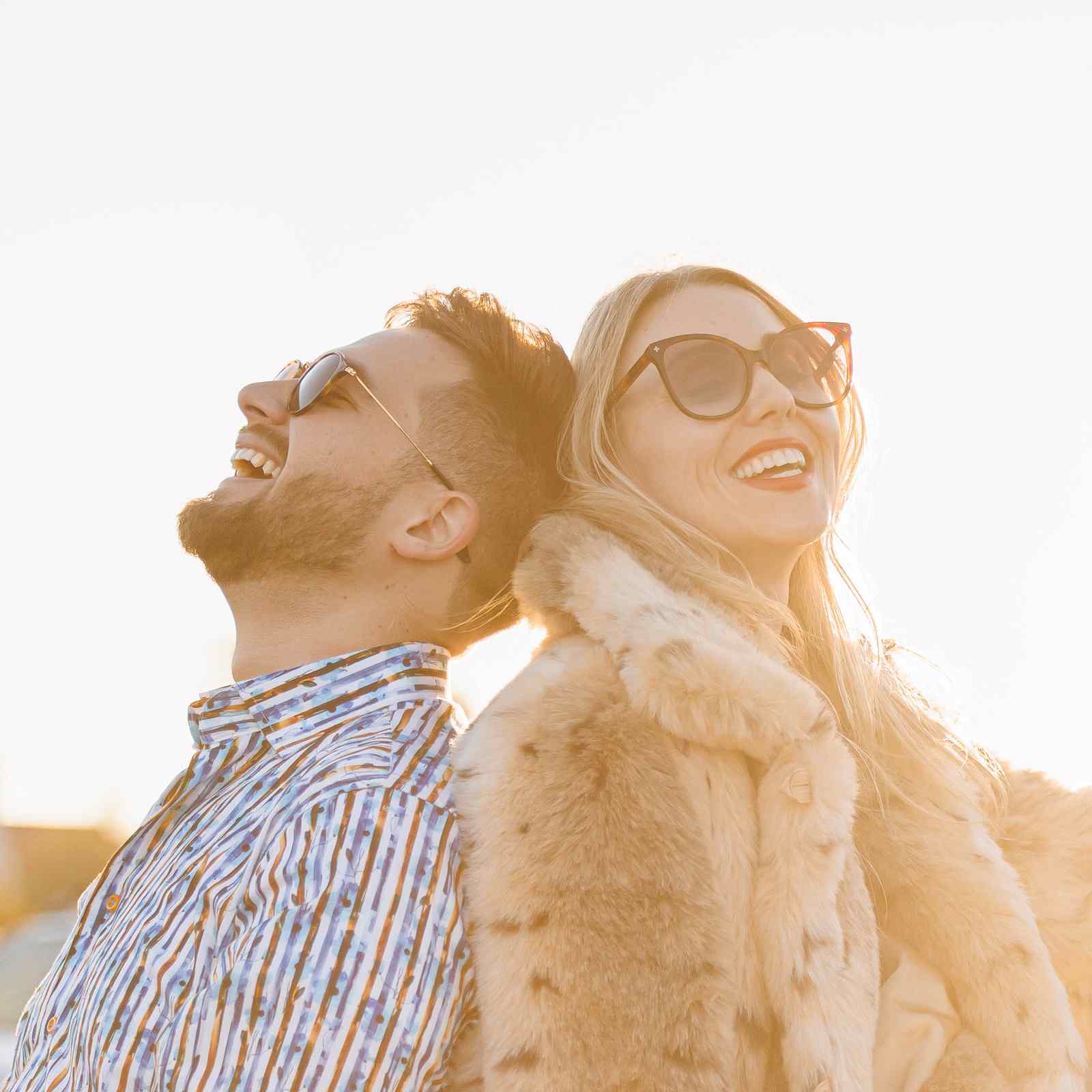 Man and woman laughing back to back on a yellow Corvette at sunset in Phoenix, Arizona