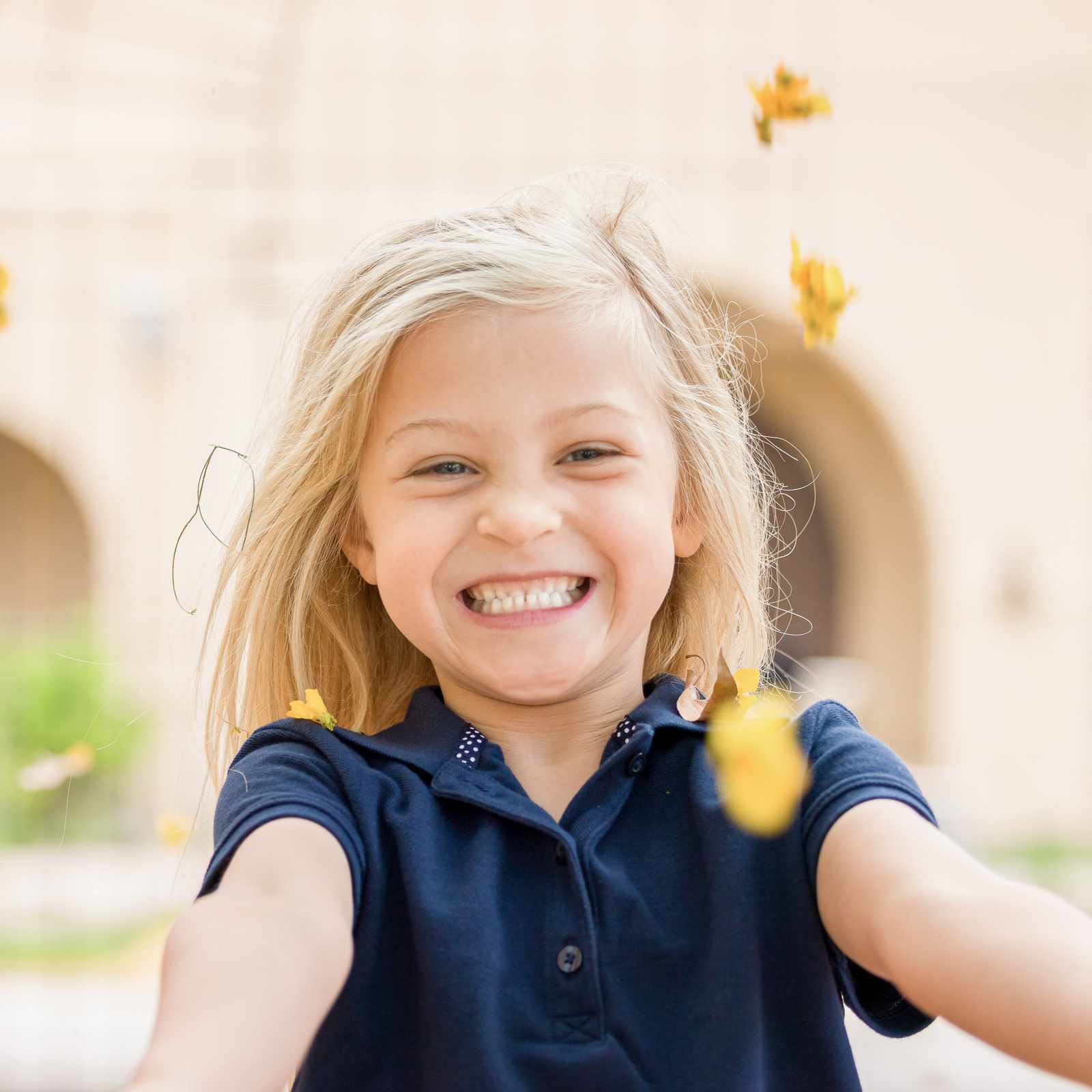 Smiling young student throwing flowers in a school courtyard