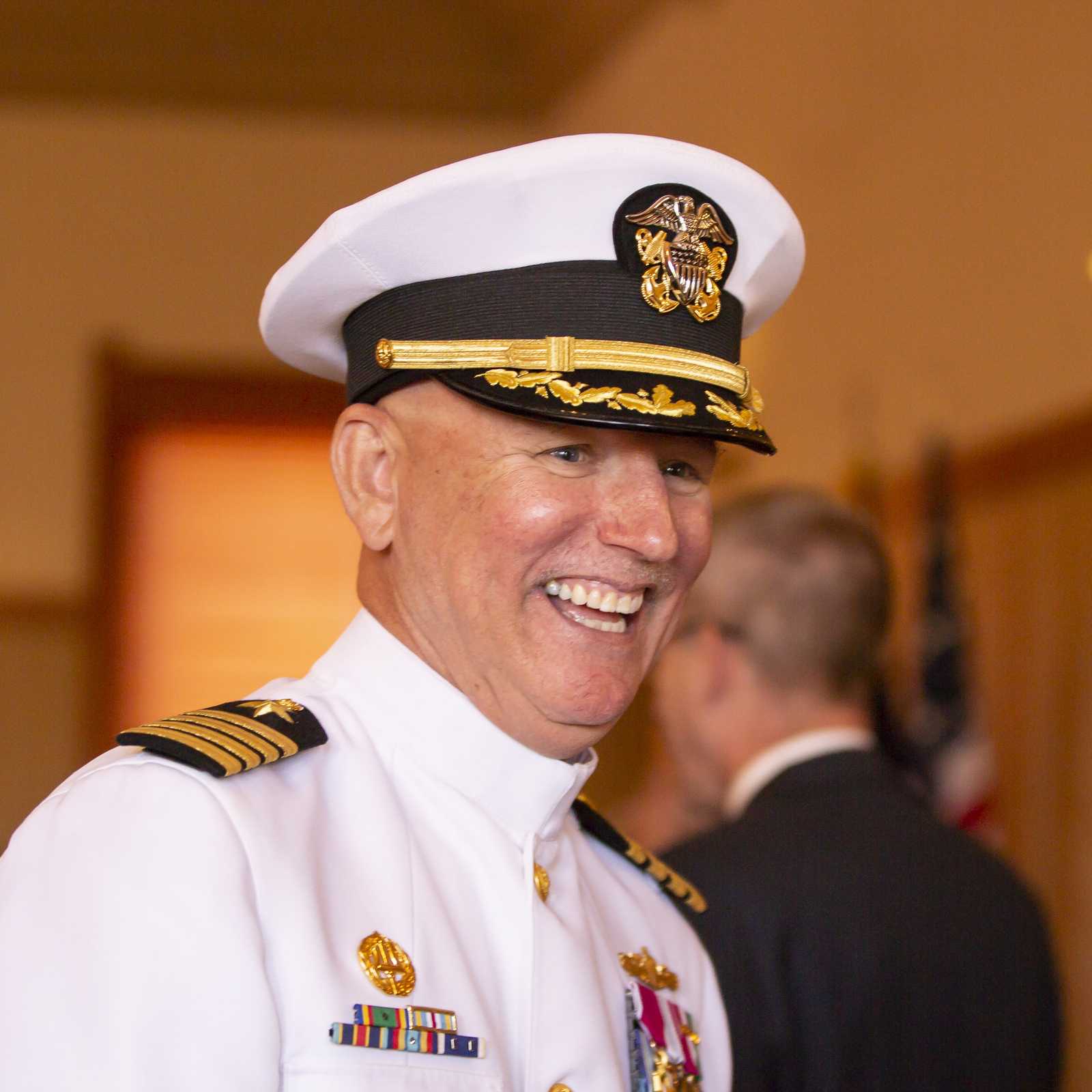 Navy captain smiling in formal dress uniform at a military event