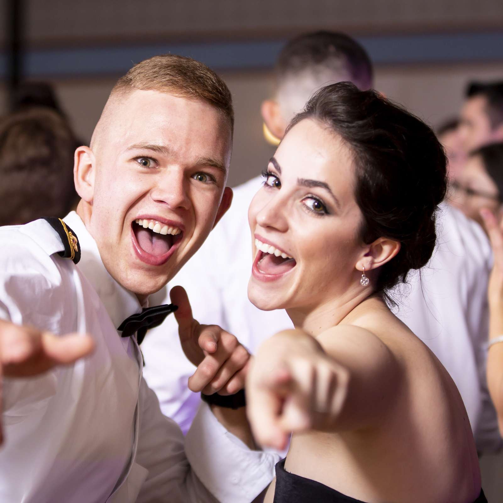 Young Navy ROTC attendees enjoying a formal dance event with joyful expressions