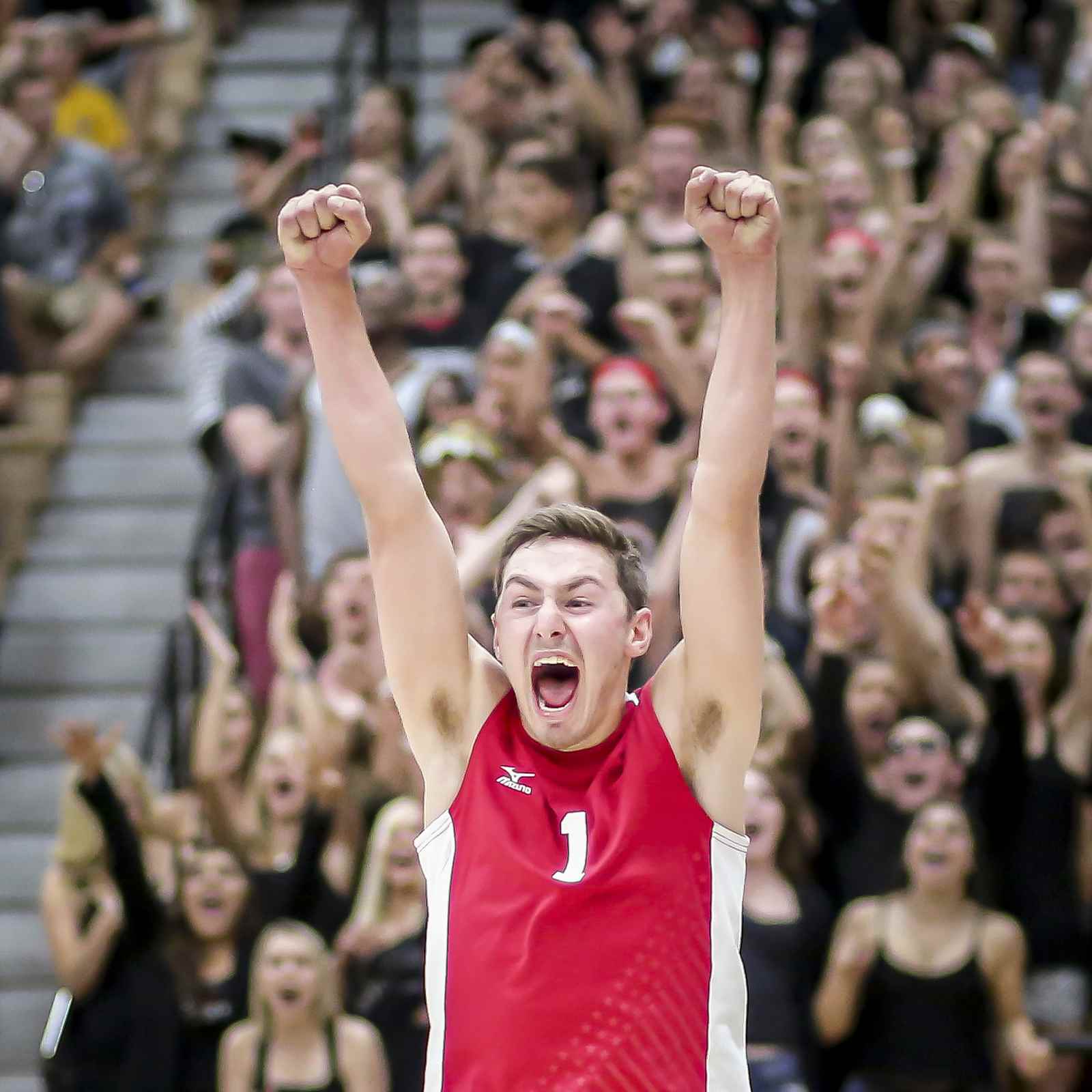 Male volleyball player celebrating with crowd in background