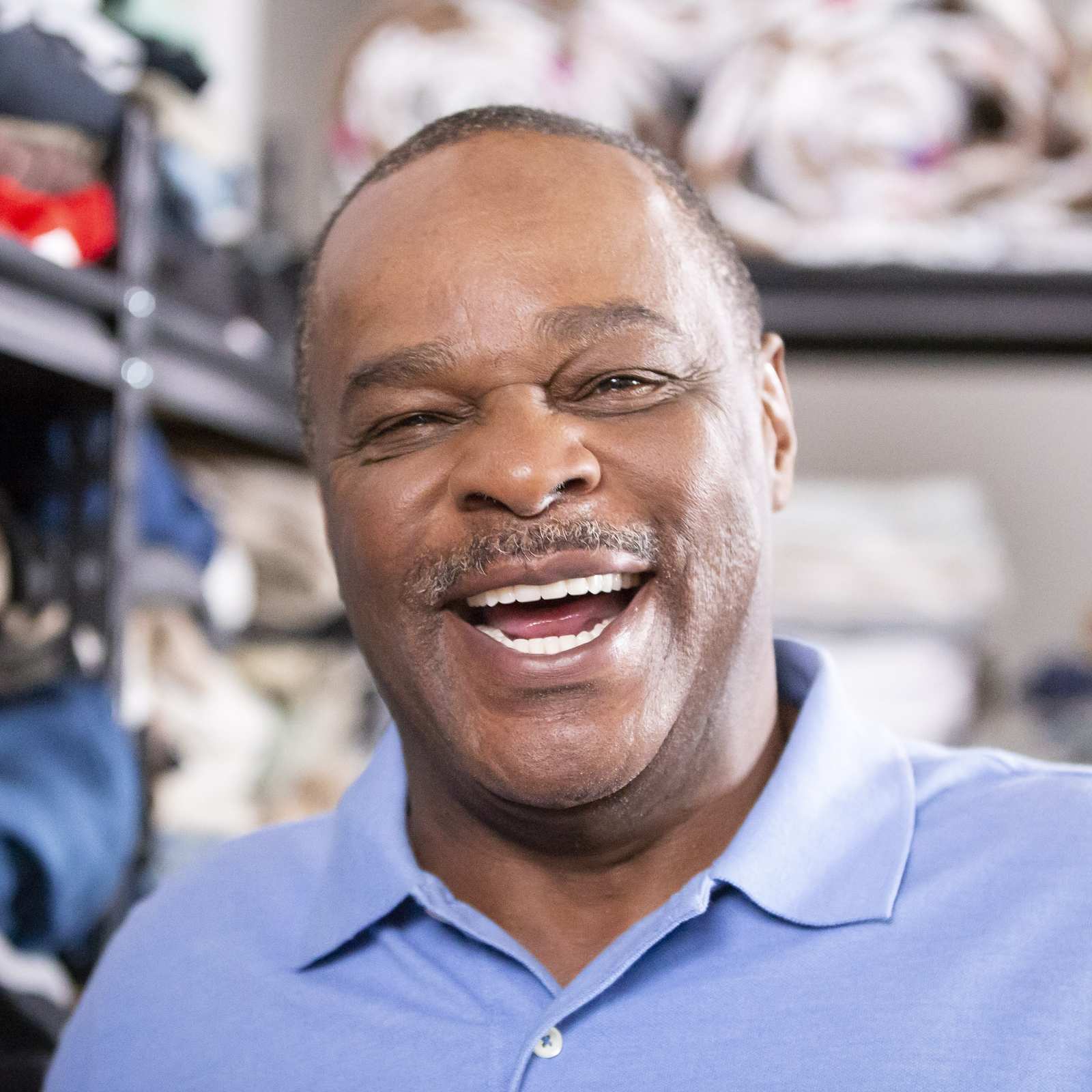 Male volunteer smiling in charity center surrounded by clothing