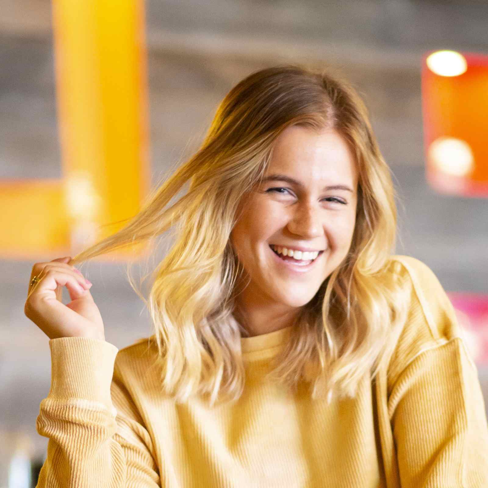 Young woman with playful expression twirling her hair at a trendy restaurant in Scottsdale, Arizona